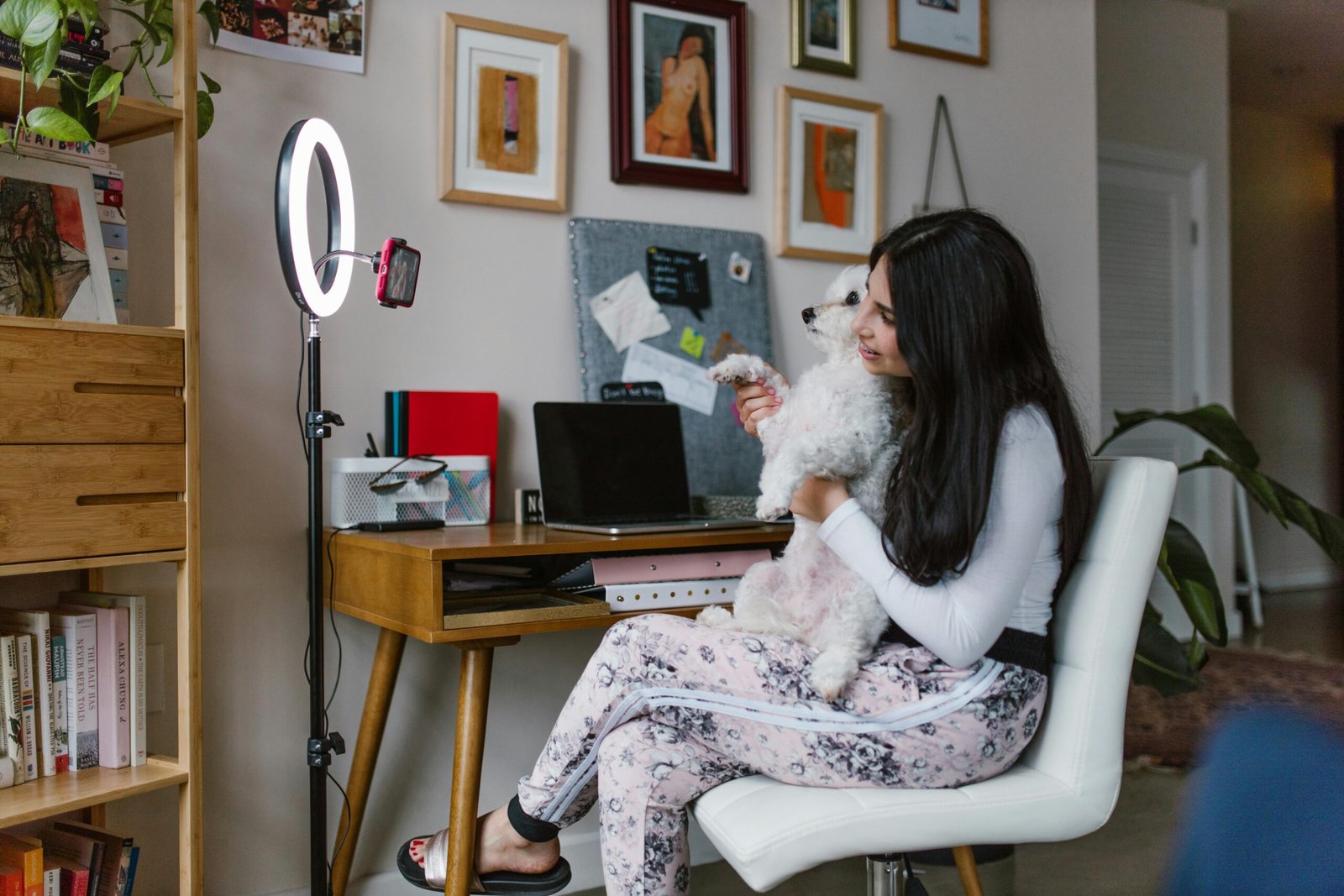 Woman using ring light for vlogging with her dog in a cozy home office setting.